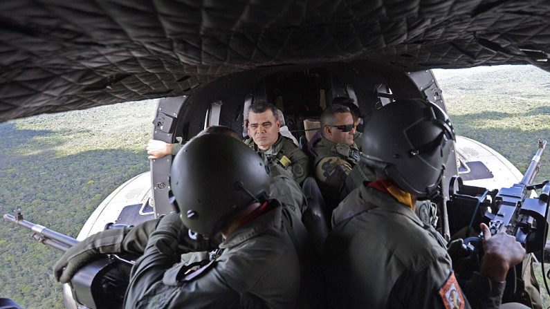 El Ministro de Defensa venezolano Vladimir Padrino López (al fondo a la izquierda) es visto en vuelo durante una gira por los campamentos mineros ilegales ubicados en el Parque Nacional Canaima, Estado Bolívar, Región de la Gran Sabana, al sudeste de Venezuela, el 16 de diciembre de 2014. (FEDERICO PARRA/AFP vía Getty Images)