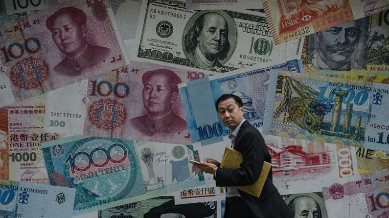 Un hombre pasa por delante de una pantalla que muestra billetes de diferentes monedas en Hong Kong el 9 de noviembre de 2016. (El crédito de la foto debe leerse ANTHONY WALLACE/AFP a través de Getty Images)
