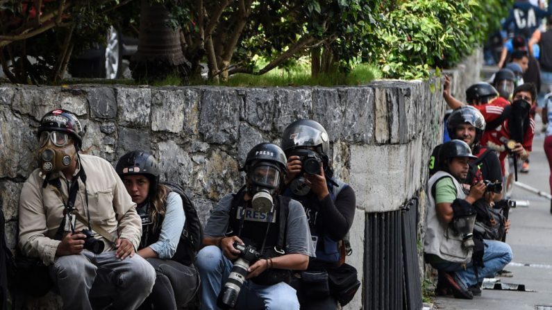 Periodistas se refugian durante los enfrentamientos entre manifestantes antigubernamentales y la policía antidisturbios cerca de la Plaza Altamira en Caracas, el 14 de junio de 2017. (El crédito de la foto debe leerse JUAN BARRETO/AFP a través de Getty Images)
