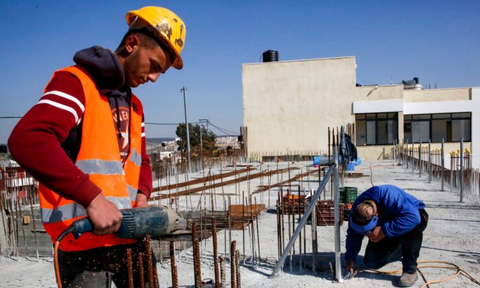 Un obrero de la construcción corta varillas de acero en el lugar donde se encuentra una escuela financiada por la Agencia de los Estados Unidos para el Desarrollo Internacional (USAID, por sus siglas en inglés) en Al-Jabaa, en la Ribera Occidental, el 22 de enero de 2019.  (HAZEM BADER/AFP a través de Getty Images)
