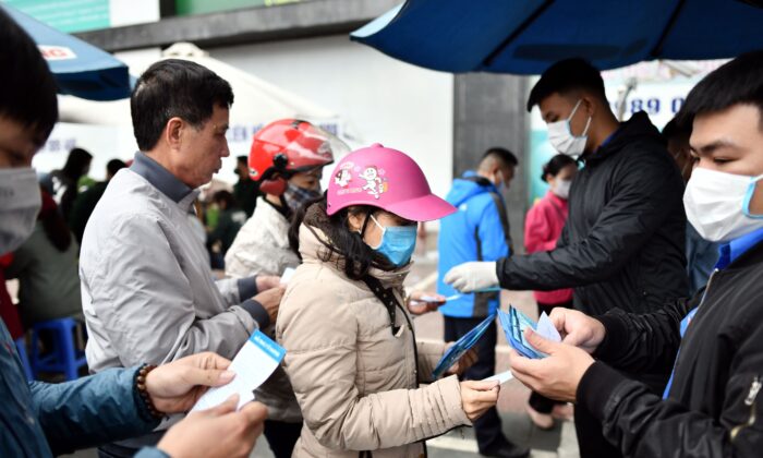 Residentes vietnamitas hacen cola para recibir mascarillas protectoras gratuitas en un centro de distribución improvisado en medio de las preocupaciones por el nuevo brote de coronavirus, en Hanoi el 8 de febrero de 2020. (Foto de MANAN VATSYAYANA/AFP vía Getty Images)