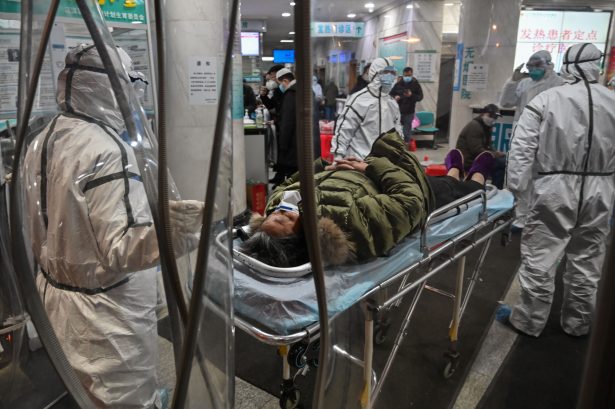 Miembros del personal médico que portan ropa protectora para ayudar a detener la propagación de un virus mortal que comenzó en la ciudad, llegan con un paciente al Hospital de la Cruz Roja de Wuhan, China, el 25 de enero de 2020. (Hector Retamal/AFP vía Getty Images)