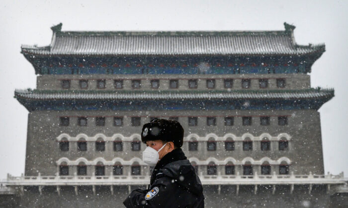 Un oficial de policía chino lleva una máscara protectora mientras hace guardia en la puerta de Qianmen durante una nevada en una calle comercial vacía y cerrada en Beijing, China, el 5 de febrero de 2020. (Kevin Frayer/Getty Images)