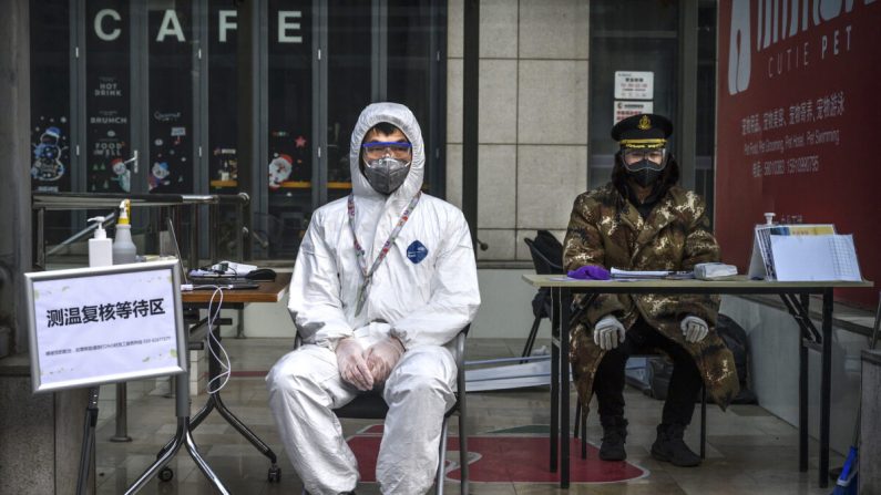 Un guardia chino lleva una máscara y un traje protector mientras espera para comprobar las temperaturas y registrar a las personas que entran en un edificio en una zona comercial de Beijing, China, el 21 de febrero de 2020. (Kevin Frayer/Getty Images)