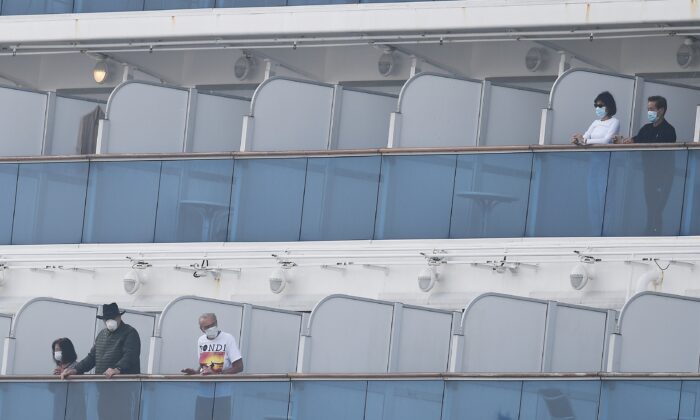 Pasajeros del crucero Diamond Princess se asoman a los balcones desde sus camarotes en la terminal de cruceros del muelle Daikoku en el puerto de Yokohama, Japón, el 14 de febrero de 2020. (Charly Triballeau/AFP vía Getty Images)