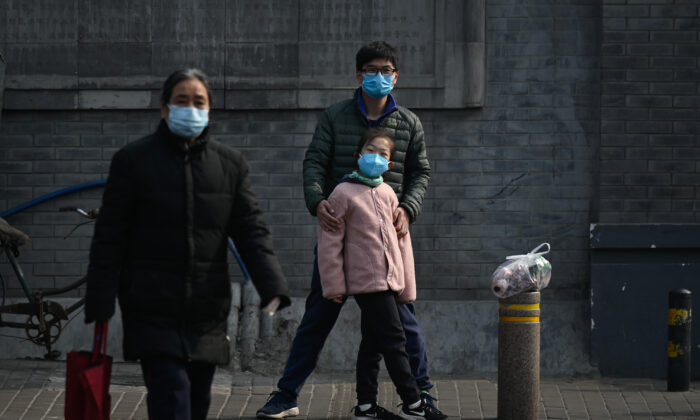 Un hombre y una niña con máscaras faciales esperan para cruzar una calle en Beijing, China, el 28 de febrero de 2020. (STR/AFP a través de Getty Images)