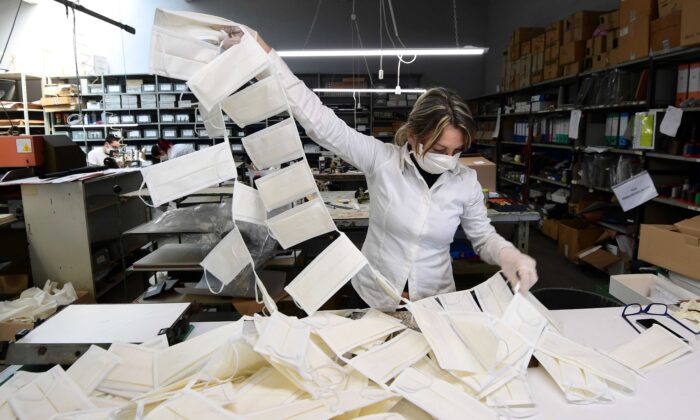 Un empleado controla las máscaras quirúrgicas en un taller de cuero convertido en una fábrica de máscaras, cerca de Vigevano, Lombardía, Italia, el 19 de marzo de 2020. (Miguel Medina/AFP vía Getty Images)