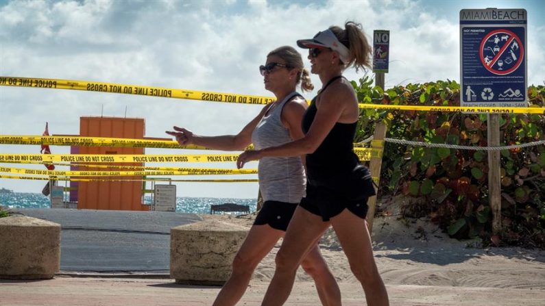 Los turistas pasan por una playa cerrada en South Beach, Florida, EE. UU., el 19 de marzo de 2020. EFE/EPA/CRISTOBAL HERRERA