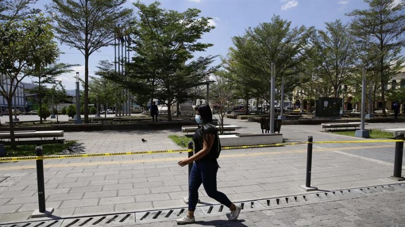 Una mujer camina frente a la Plaza Libertad este martes en San Salvador (El Salvador). Plazas y parques públicos han sido cerrados al público en general para evitar aglomeraciones de personas ante la pandemia de coronavirus.  EFE/Rodrigo Sura
