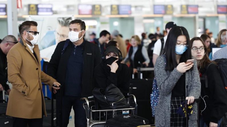 Varios viajeros esperan en una cola frente a los mostradores de facturación del aeropuerto de El Prat-Barcelona, en Barcelona, Cataluña, noreste de España, el 13 de marzo de 2020. EFE/Alejandro García
