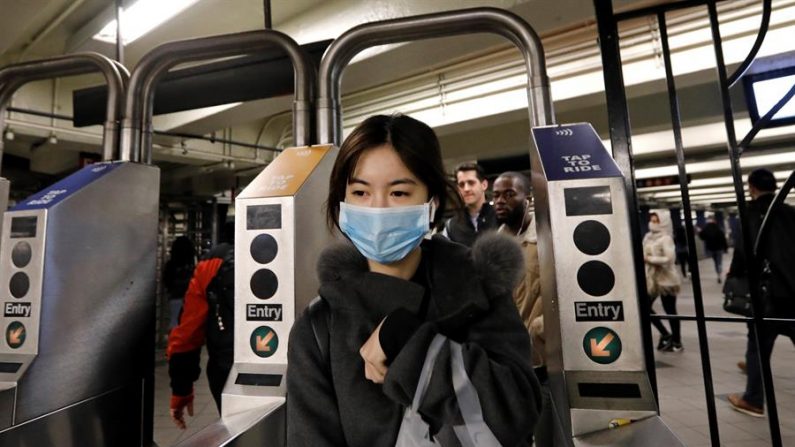 Una mujer fue registrada este jueves al protegerse con un tapabocas, a la salida del metro en la estación de Columbus Circle en New York (EE.UU.). EFE/Peter Foley
