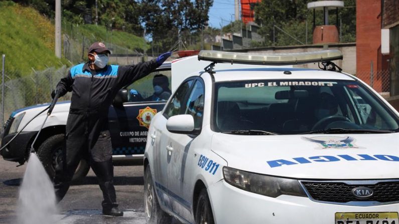 Agentes de la Policía Metropolitana de Quito fueron registrados este jueves al desinfectar sus patrullas, a las puertas del Cuartel General en Loma de Puengasi, a las afueras de la capital ecuatoriana. EFE/Elías L. Benarroch
