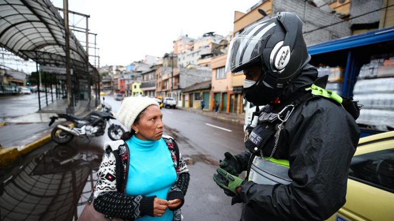 Un policía fue registrado este martes al abordar a una ciudadana, durante los controles en las calles por el Covid-19, en Quito (Ecuador). EFE/José Jácome

