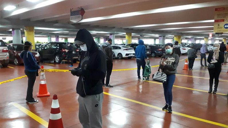 Ciudadanos de la ciudad de Quito fueron registrados este lunes al hacer fila y guardar prudente distancia, en el aparcamiento de uno de los principales supermercados de la capital ecuatoriana, en medio de las medidas de contención ante la pandemia del virus del PCCh. EFE/Elías L. Benarroch

