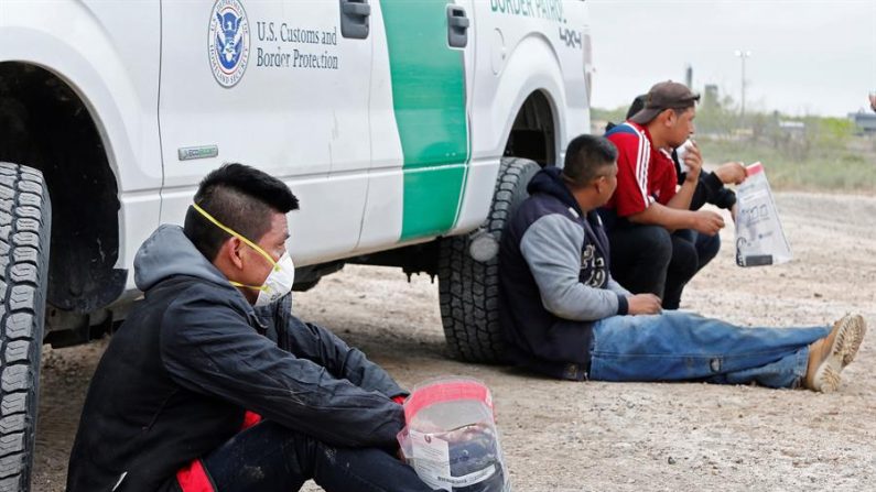 Personas detenidas y sospechosas de cruzar el Río Grande para entrar ilegalmente en los Estados Unidos esperan a que se las lleven los agentes de la Patrulla Fronteriza de Estados Unidos cerca de McAllen, Texas, EE.UU. EFE/EPA/Larry W. Smith
