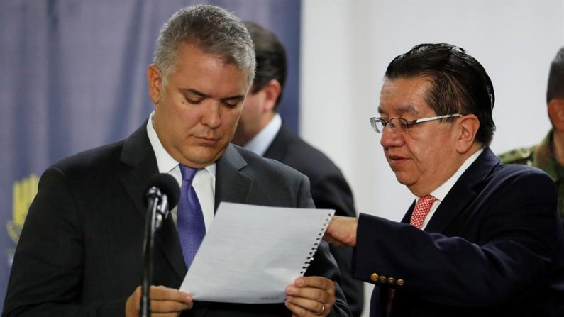 El presidente de Colombia, Iván Duque (i), lee una hoja de papel junto al ministro de Salud colombiano, Fernando Ruíz (d), antes de dirigirse a los medios en una rueda de prensa este jueves, en Bogotá (Colombia).  EFE/ Carlos Ortega
