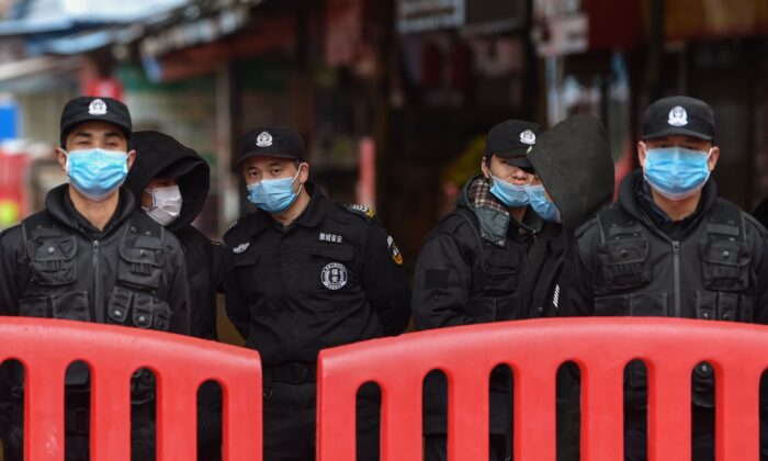 El 24 de enero de 2020, oficiales de policía y guardias de seguridad se encuentran frente al mercado mayorista de mariscos de Huanan en Wuhan. (HECTOR RETAMAL / AFP a través de Getty Images)