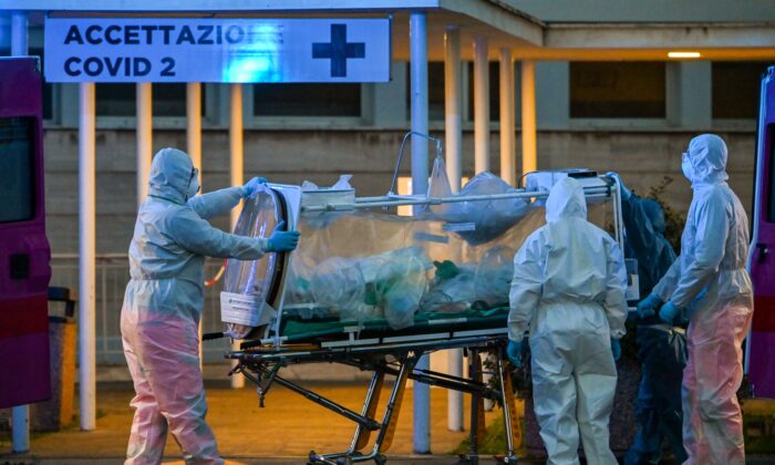 Varios profesionales sanitarios con mono de trabajo trasladan a un paciente en cuidados intensivos al recién construido hospital temporal Columbus Covid 2, en el hospital Gemelli de Roma, el 16 de marzo de 2020. (Andreas Solaro/AFP vía Getty Images)