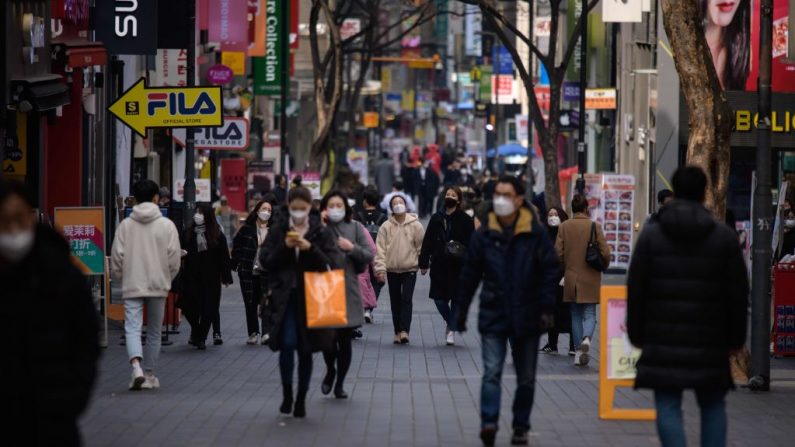 Peatones con máscaras faciales, en medio de la pandemia de COVID-19, caminan por el distrito comercial de Myeongdong en Seúl (Corea del Sur) el 6 de marzo de 2020. (Ed Jones/AFP vía Getty Images)