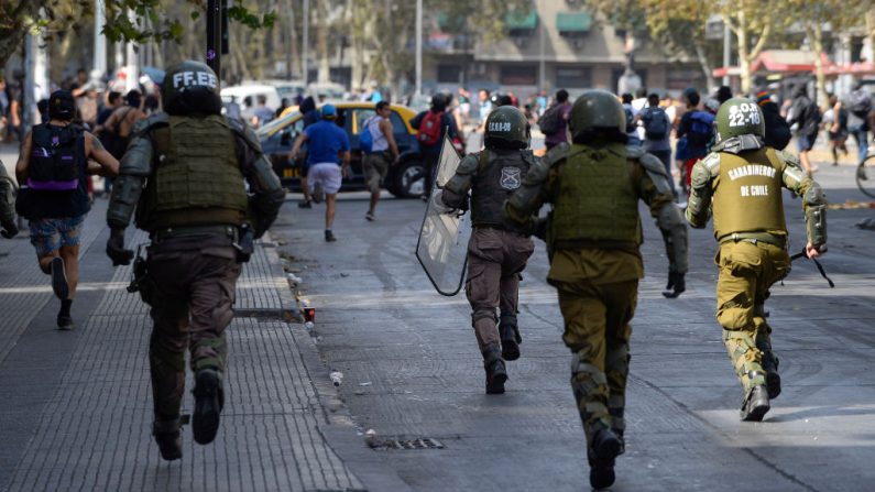 Agentes de la policía antidisturbios corren a dispersar a los manifestantes durante las protestas contra el gobierno de Sebastián Piñera en su segundo aniversario, el 11 de marzo de 2020 en Santiago de Chile. (Claudio Santana/Getty Images)