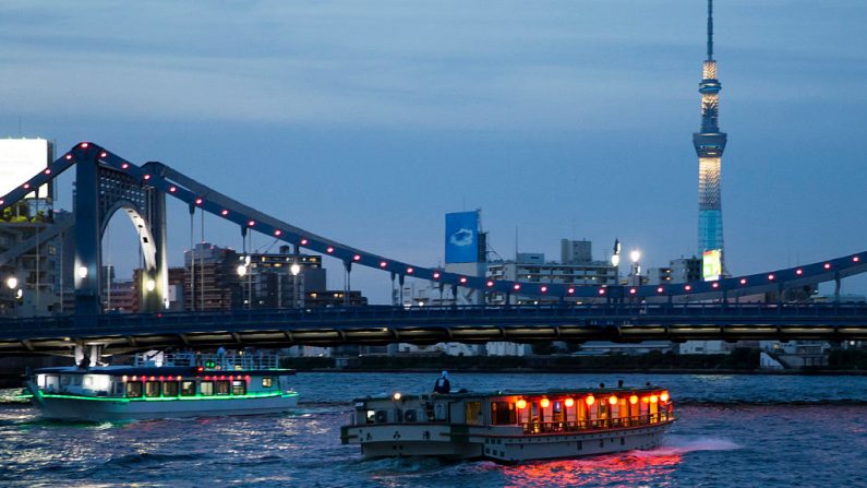 Los barcos tradicionales Yakatabune de estilo barcaza baja navegan por el Río Sumida mientras el Skytree de Tokio se ilumina al atardecer del 11 de junio de 2016 en Tokio, Japón. (Tomohiro Ohsumi/Getty Images)