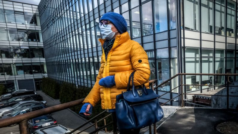 Una mujer con una máscara facial, en medio de la preocupación por el virus del PCCh, pasa por delante de un edificio de oficinas en el centro de Moscú, Rusia, el 24 de marzo de 2020. (YURI KADOBNOV/AFP vía Getty Images)