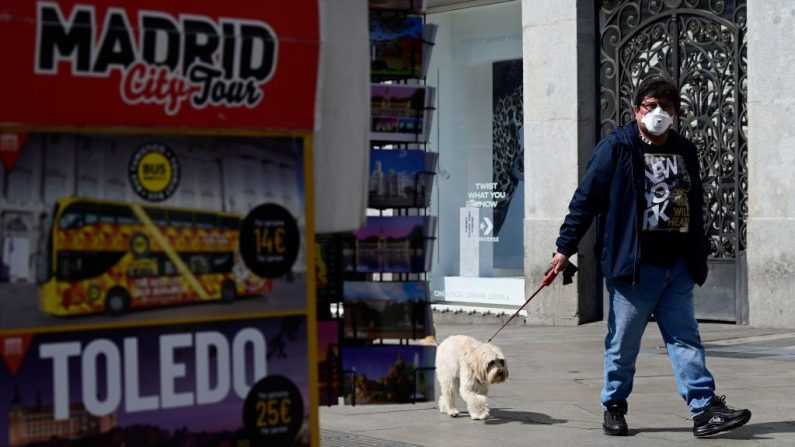 Un hombre con una máscara facial pasea a su perro en Madrid, España, el 14 de marzo de 2020 después de que las autoridades regionales ordenaran cerrar todas las tiendas de la región desde hoy hasta el 26 de marzo, excepto las que venden comida, farmacias y gasolineras, para frenar la propagación del coronavirus. (JAVIER SORIANO/AFP vía Getty Images)