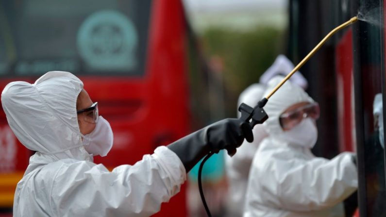 Los trabajadores lavan y desinfectan un autobús en la estación de autobuses, como medida para prevenir la propagación del nuevo Coronavirus, COVID-19, en Bogotá, Colombia, el 15 de marzo de 2020. (RAUL ARBOLEDA/AFP vía Getty Images)