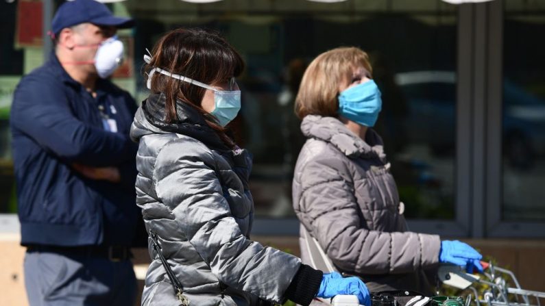 Residentes con una máscara protectora esperan para hacer sus compras fuera de un supermercado en Codogno, al sureste de Milán, Italia, el 11 de marzo de 2020, un día después de que Italia impusiera el martes restricciones nacionales sin precedentes a sus 60 millones de personas para controlar el mortal coronavirus COVID-19. (MIGUEL MEDINA/AFP vía Getty Images)