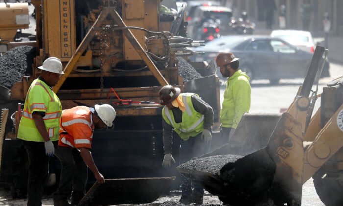 Trabajadores de construcción alisan el alquitrán mientras pavimentan una carretera en San Francisco el 5 de octubre de 2018. (Justin Sullivan/Getty Images)