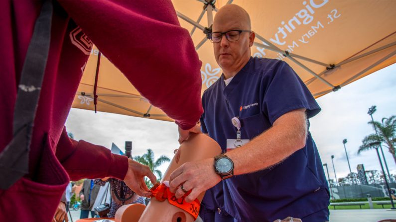 El enfermero Terry Liddell muestra a un estudiante cómo aplicar un torniquete mientras las enfermeras de trauma del Centro Médico St. Mary dirigen una demostración de entrenamiento de aplicación preventiva de torniquetes en la Universidad Estatal de California, Long Beach, el 9 de mayo de 2019. (David McNew/Getty Images)