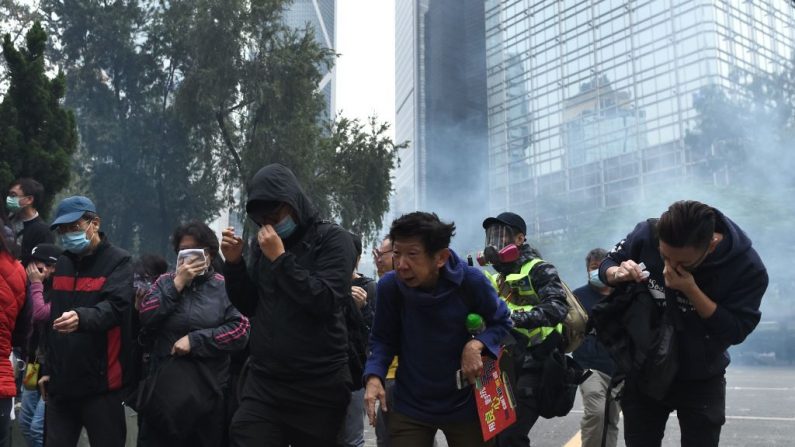 La gente reacciona a los gases lacrimógenos disparados por la policía para dispersar a la multitud reunida para el "bloqueo universal a los comunistas" en el Chater Garden en Hong Kong el 19 de enero de 2020. (PHILIP FONG/AFP vía Getty Images)