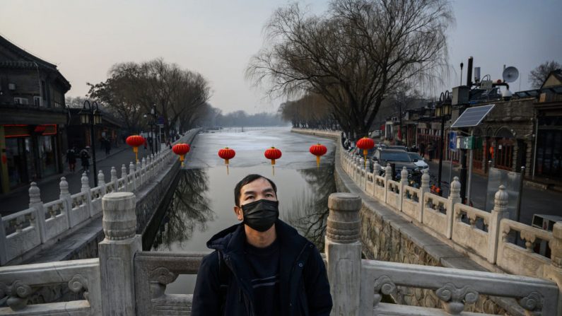 Un hombre chino usa una máscara protectora mientras está de pie en un puente en el lago Houhai, que generalmente estaría abarrotado en este momento, durante el Año Nuevo Chino y el Festival de Primavera, el 26 de enero de 2020, en Beijing, China. (Kevin Frayer/Getty Images)