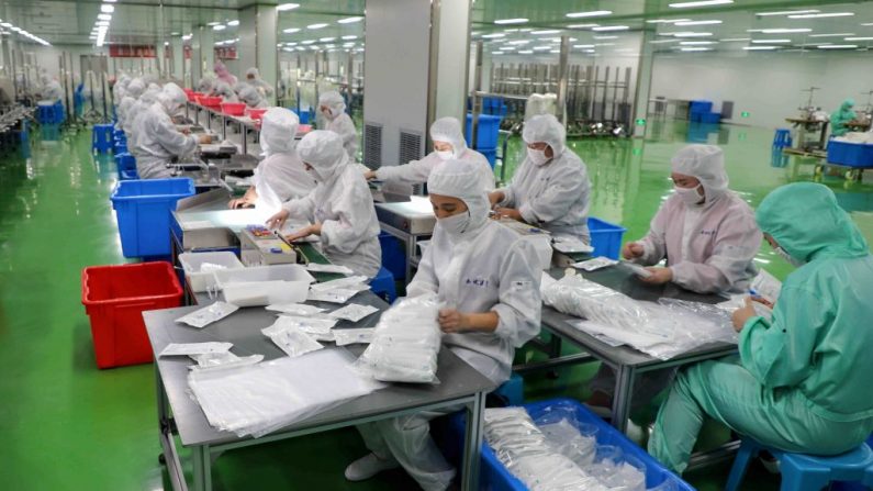 Trabajadores fabrican trajes protectores en una fábrica en la ciudad de Binzhou de la provincia oriental china de Shandong el 13 de febrero de 2020. (STR / AFP a través de Getty Images)