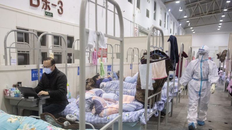 Esta foto tomada el 17 de febrero de 2020 muestra a un hombre (L) que ha mostrado síntomas leves del coronavirus COVID-19 usando un ordenador portátil en un centro de exposiciones convertido en un hospital en Wuhan en la provincia central de Hubei en China. (Imagen de contexto de STR/AFP vía Getty Images)
