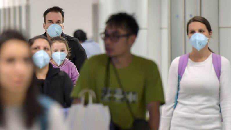 Los pasajeros, usando máscaras como medida de precaución para evitar contraer el virus Covid-19, viajan a través del Aeropuerto Internacional de Guarulhos, en Guarulhos, Sao Paulo, Brasil, el 26 de febrero de 2020.  (Foto de NELSON ALMEIDA/AFP vía Getty Images)
