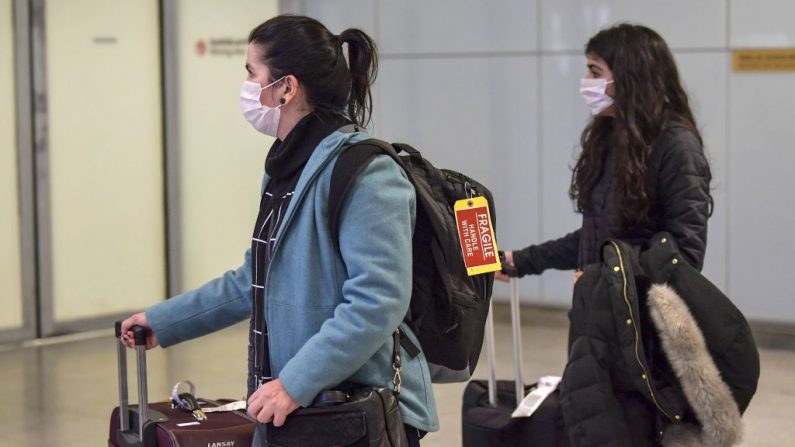 Los pasajeros, usando máscaras como medida de precaución para evitar contraer el virus Covid-19, viajan a través del Aeropuerto Internacional de Guarulhos, en Guarulhos, Sao Paulo, Brasil, el 26 de febrero de 2020. (NELSON ALMEIDA/AFP vía Getty Images)