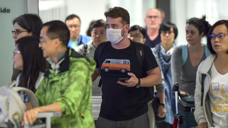 Un pasajero, usando una máscara como medida de precaución para evitar contraer el virus del PCCh, viaja a través del Aeropuerto Internacional de Guarulhos, en Guarulhos, Sao Paulo, Brasil, el 26 de febrero de 2020. (NELSON ALMEIDA/AFP vía Getty Images)