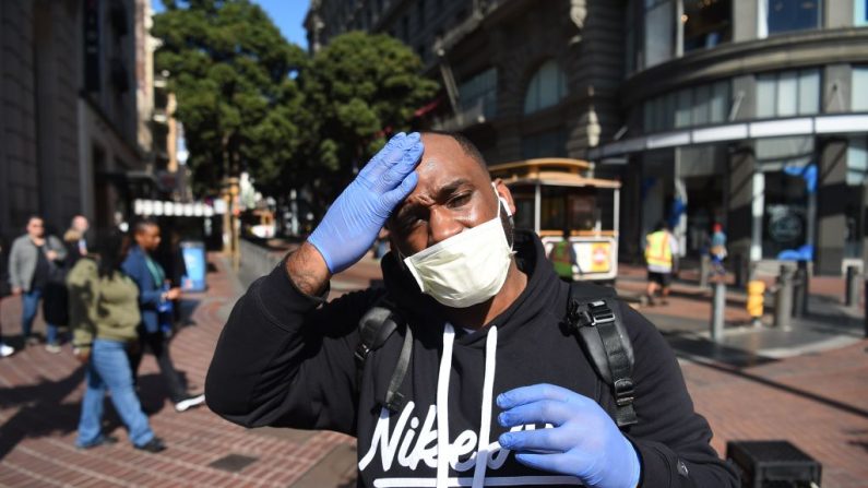 Un hombre se ajusta la máscara y los guantes, como precaución para protegerse del coronavirus, mientras camina por el teleférico en San Francisco, California, el 27 de febrero de 2020. (Foto de Josh EDELSON / AFP) (Foto de JOSH EDELSON/AFP vía Getty Images)
