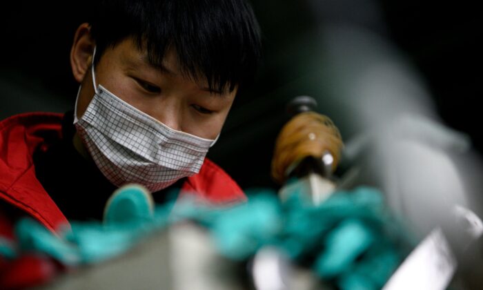 Un trabajador con mascarilla hace plantillas en la fábrica de Zhejiang Xuda Shoes Co. en Wenzhou, China, el 27 de febrero de 2020. (NOEL CELIS/AFP vía Getty Images)