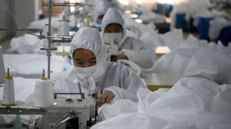 Trabajadores cosen trajes de materiales para ser usados en el brote de coronavirus COVID-19 en la fábrica de ropa de la Industria del Ugly Duck de Zhejiang en Wenzhou el 28 de febrero de 2020. (NOEL CELIS/AFP vía Getty Images)