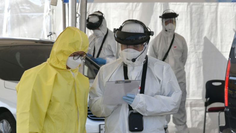 Miembros médicos que usan equipo de protección hablan mientras revisan a conductores con síntomas sospechosos del nuevo coronavirus, en Goyang, Corea del Sur, el 29 de febrero de 2020. (Jung Yeon-je/AFP vía Getty Images)