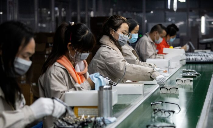 Esta foto, tomada el 28 de febrero de 2020, muestra a trabajadores con máscaras faciales puliendo marcos de anteojos en la Azure Eyeglasses Company, en Wenzhou, China. (Noel Celis/AFP a través de Getty Images)