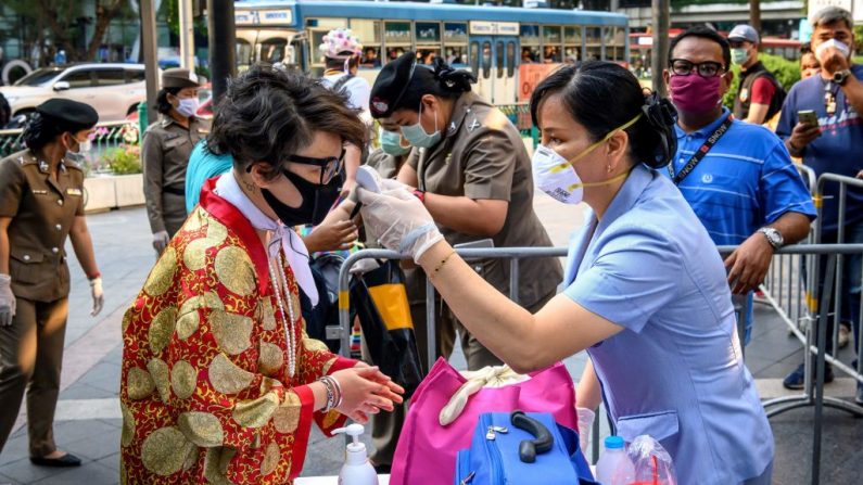 Una funcionaria de salud, con una máscara facial en medio de los temores sobre la propagación del nuevo coronavirus COVID-19, verifica la temperatura corporal de un manifestante antes de una manifestación antigubernamental en Bangkok el 1 de marzo de 2020. (MLADEN ANTONOV/AFP/Getty Images)