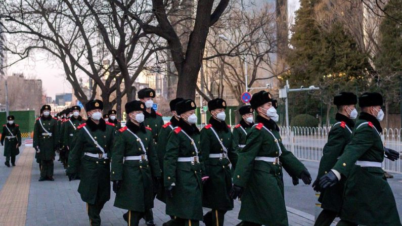 Esta foto tomada el 1 de marzo de 2020 muestra a oficiales de policía paramilitar con máscaras faciales mientras caminan por una calle en Beijing, China. (NICOLAS ASFOURI/AFP vía Getty Images)