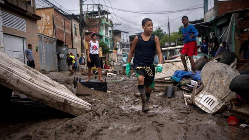 Los niños caminan en el barro después de las fuertes lluvias durante el fin de semana, en el barrio de Realengo, en los suburbios de Río de Janeiro, Brasil, el 2 de marzo de 2020. (MAURO PIMENTEL / AFP/Getty Images )