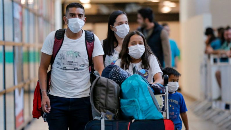 Los pasajeros caminan con máscaras protectoras como medida preventiva contra la propagación del coronavirus COVID-19, en el Aeropuerto Internacional Arturo Merino Benítez, en Santiago (Chile), el 3 de marzo de 2020. (JAVIER TORRES/AFP vía Getty Images)