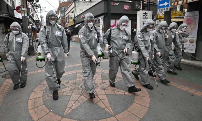 Soldados coreanos que llevan ropa protectora rocían desinfectante para ayudar a prevenir la propagación del nuevo coronavirus en un distrito comercial de Seúl el 4 de marzo de 2020. (Jung Yeon-je/AFP vía Getty Images)