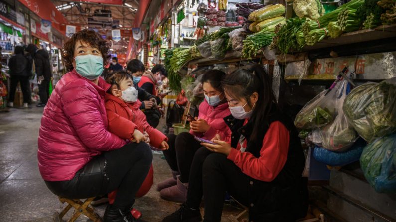  Vendedoras de vegetales chinos usan máscaras protectoras mientras esperan a los clientes en un mercado local en Beijing, China, el 4 de marzo de 2020. (Kevin Frayer/Getty Images)
