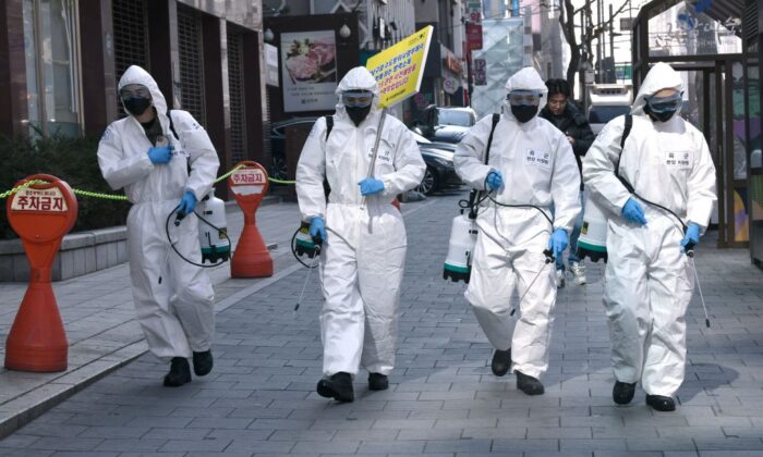 Soldados surcoreanos con equipo de protección rocían desinfectante en la calle para ayudar a prevenir la propagación del nuevo coronavirus, en el distrito de Gangnam en Seúl el 5 de marzo de 2020. (Jung Yeon-je/AFP vía Getty Images)
